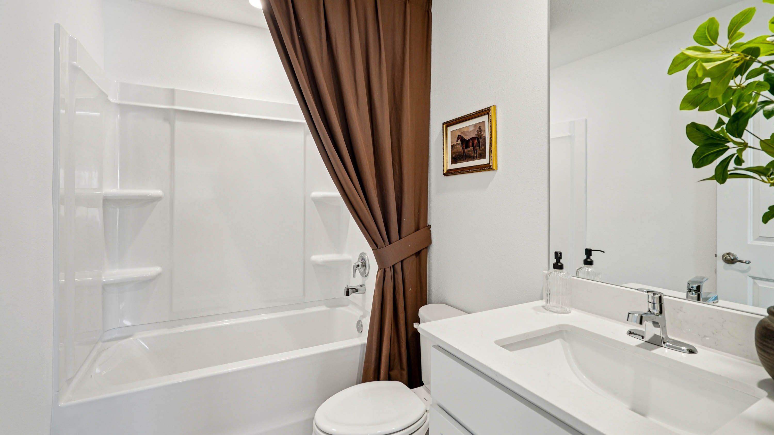 Modern bathroom with double vanity, large wall mirror, cabinets and quartz countertops along with toilet and walk-in shower