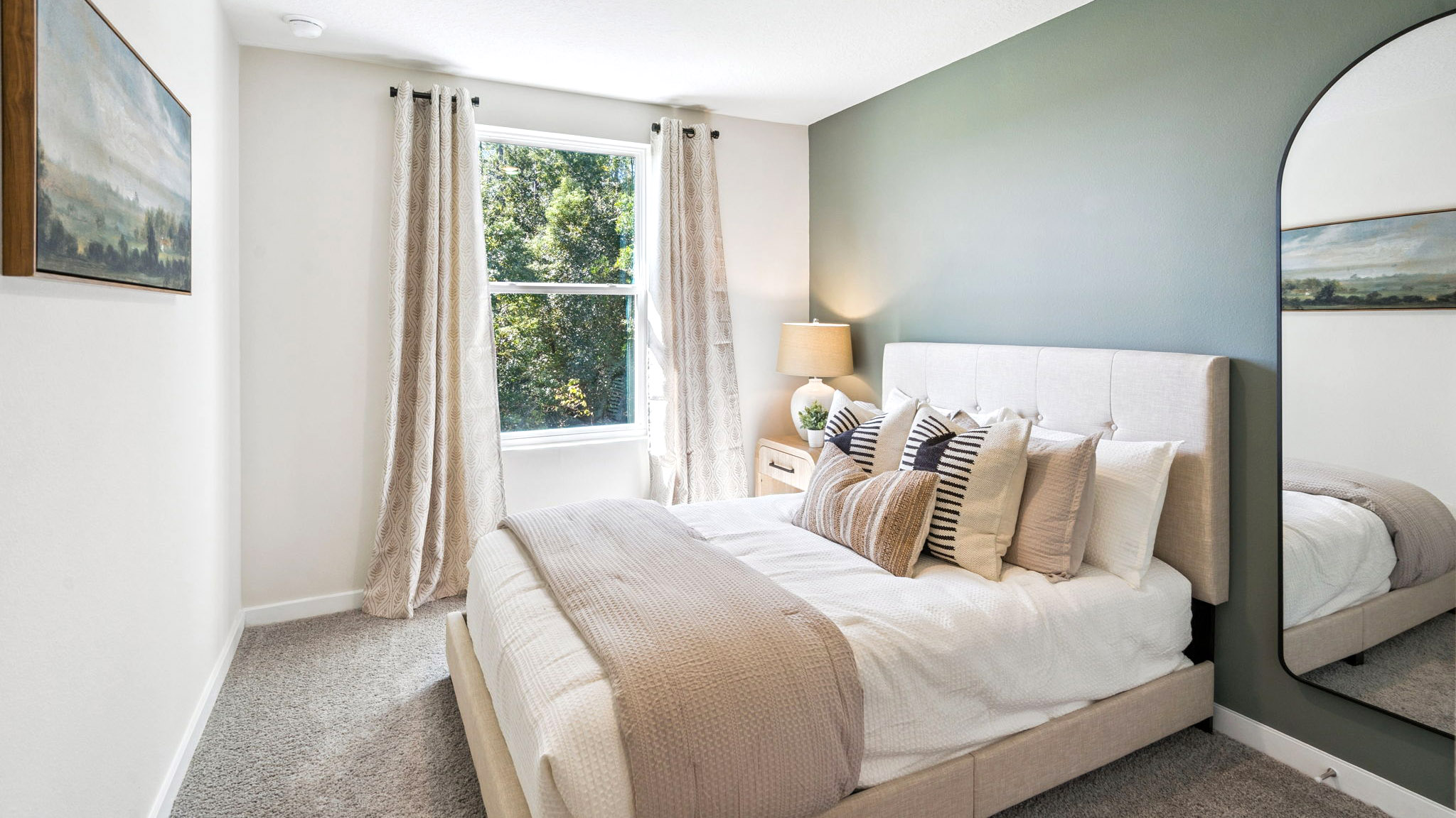 Spacious primary bedroom with king size bed, carpet flooring, natural lighting.