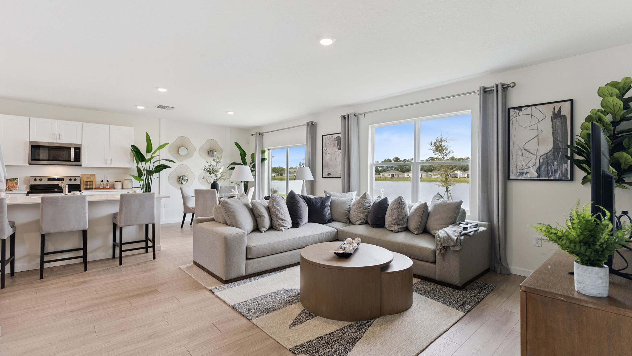 Living area with couch seating, natural lighting, laminate flooring.