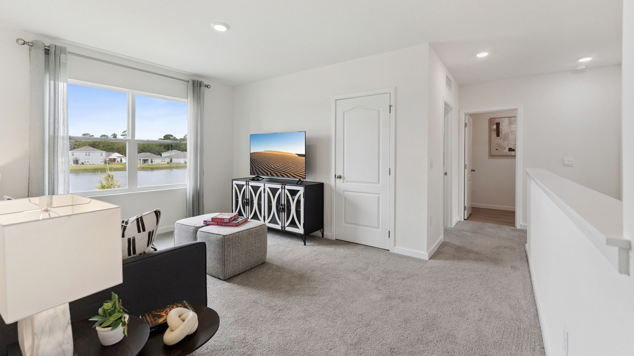 Living area with couch seating, natural lighting, laminate flooring.