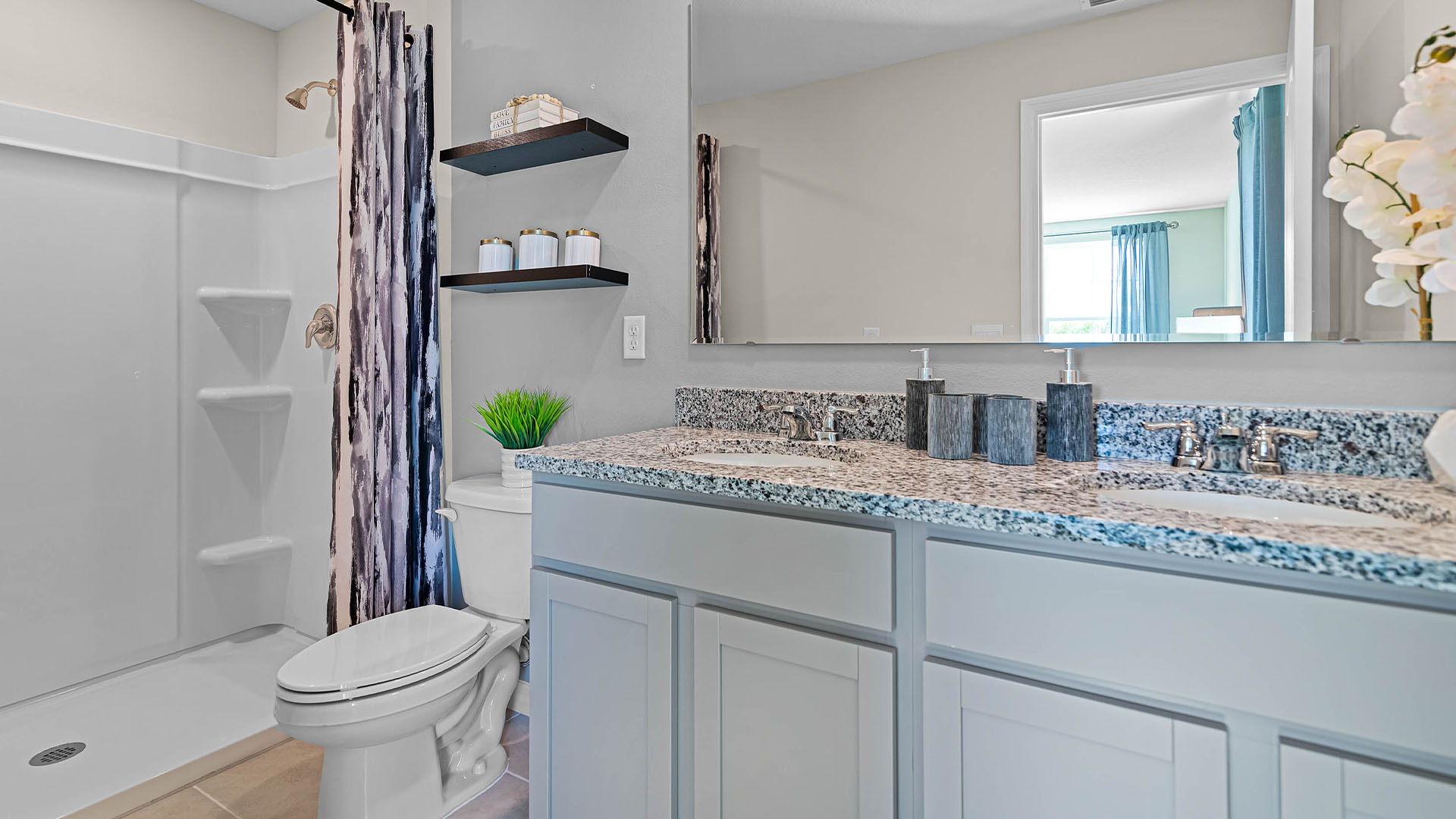 Modern bathroom with double vanity sinks, large wall mirror, cabinets and granite countertops.