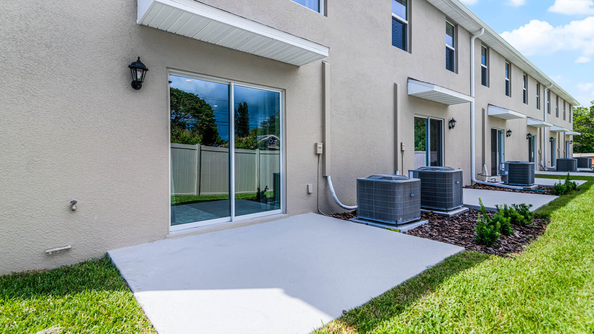 Rear of home with view of grassed backyard, porch seating and slider glass doors.