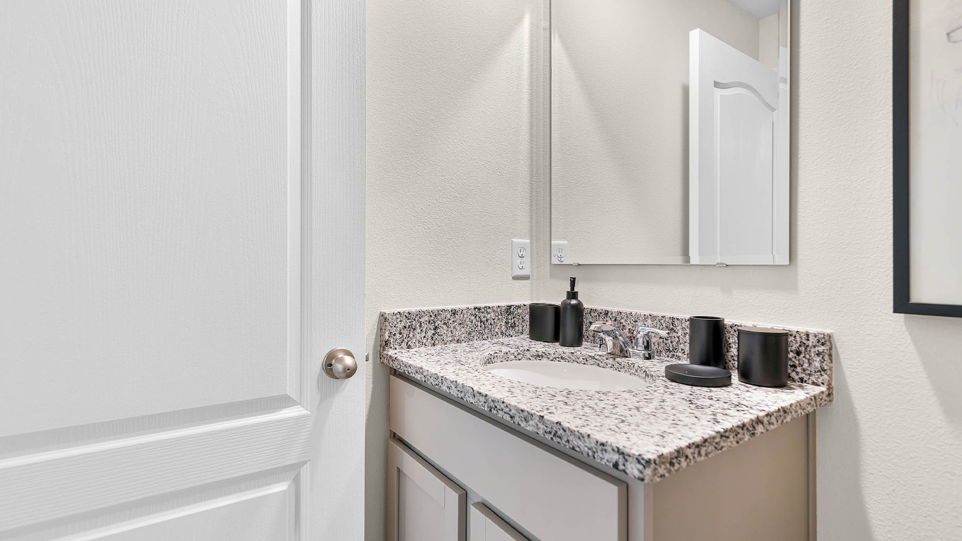Modern bathroom with single bowl sink, granite vanity, wall mirror, cabinets and toilet.