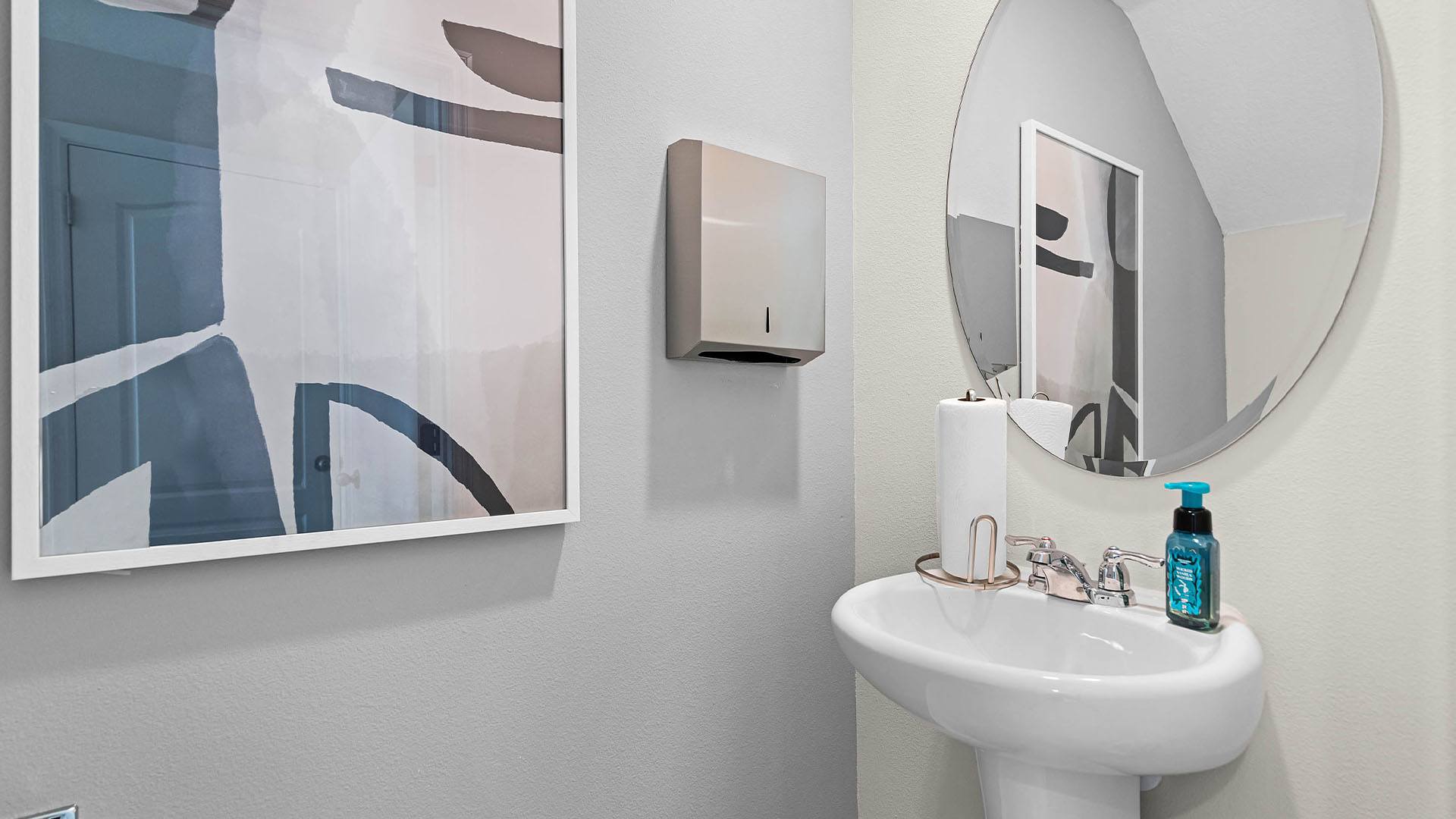 Modern bathroom with single bowl sink, granite vanity, wall mirror, cabinets and toilet.