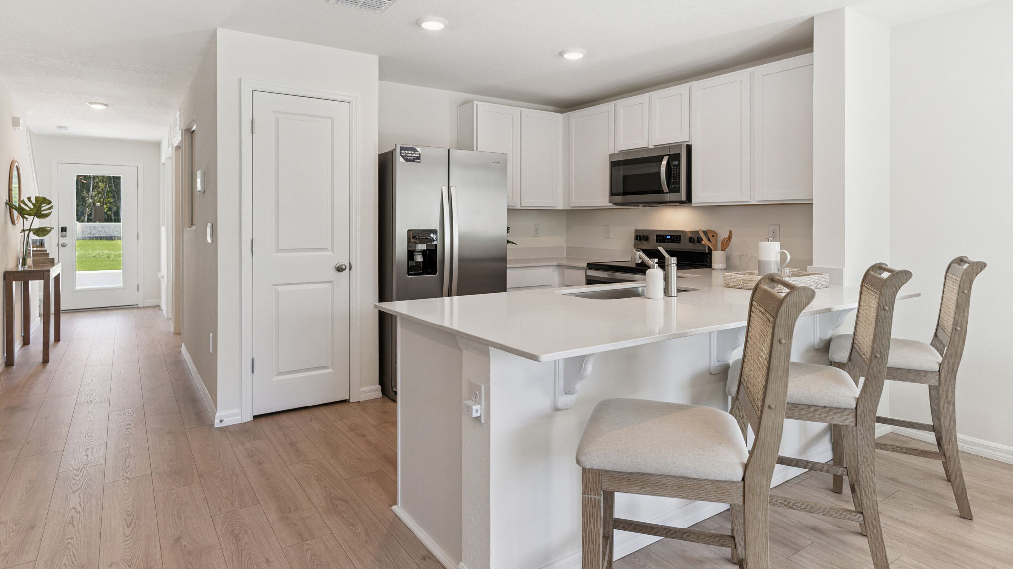 Kitchen with island seating, quartz counters, spacious pantry and stainless steel appliances.