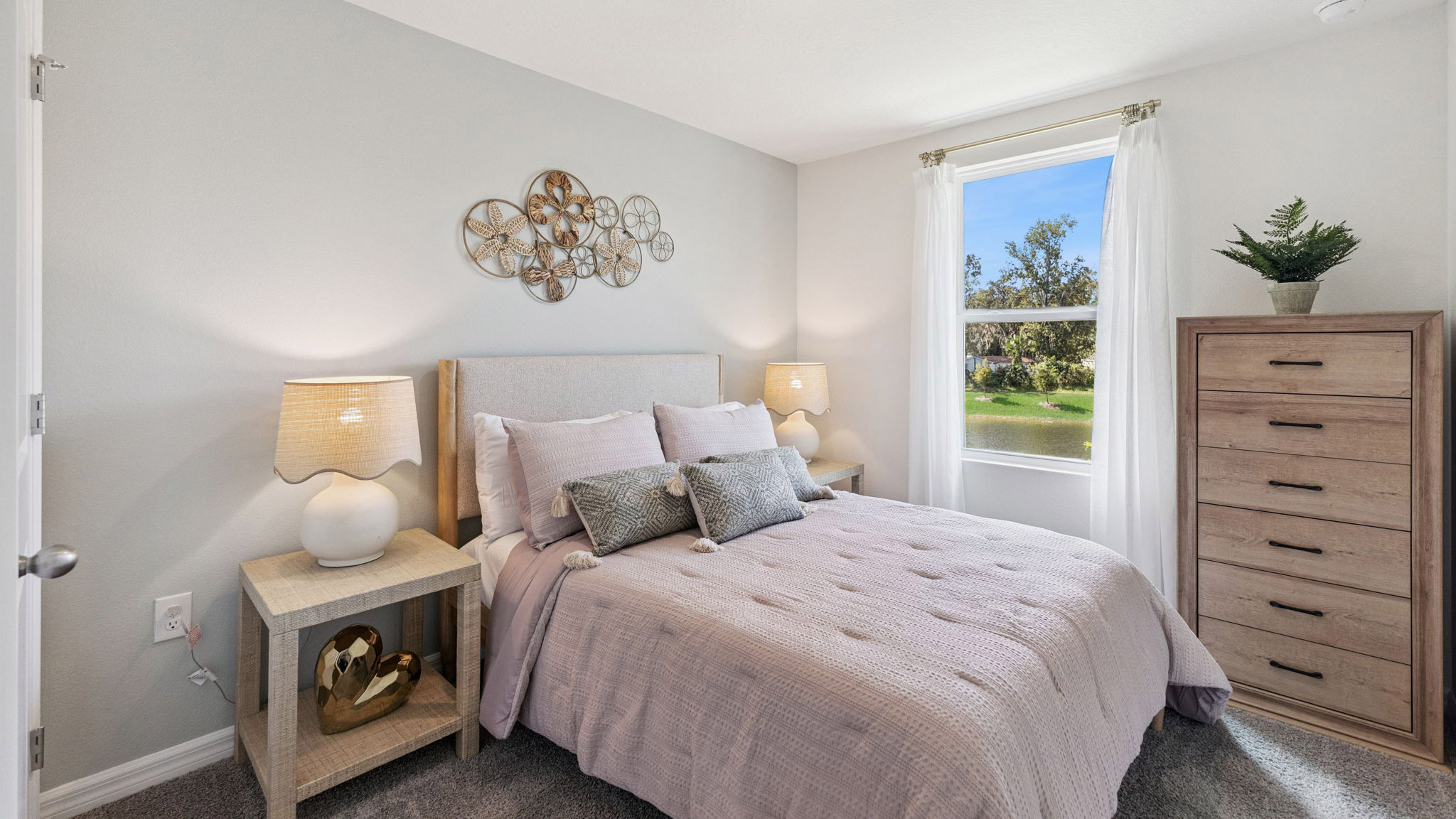Spacious primary bedroom with king size bed, carpet flooring, natural lighting.
