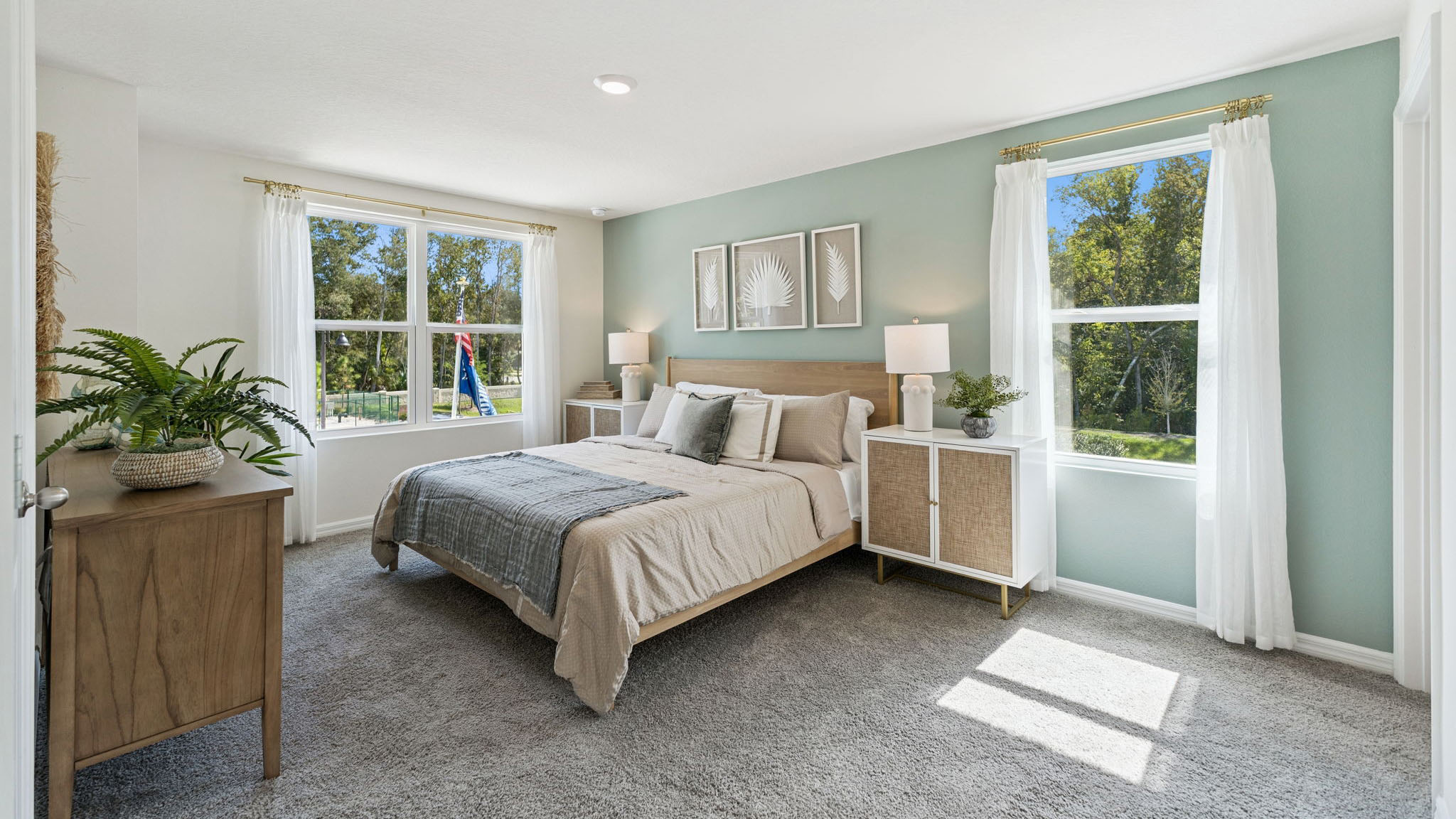 Spacious primary bedroom with king size bed, carpet flooring, natural lighting.