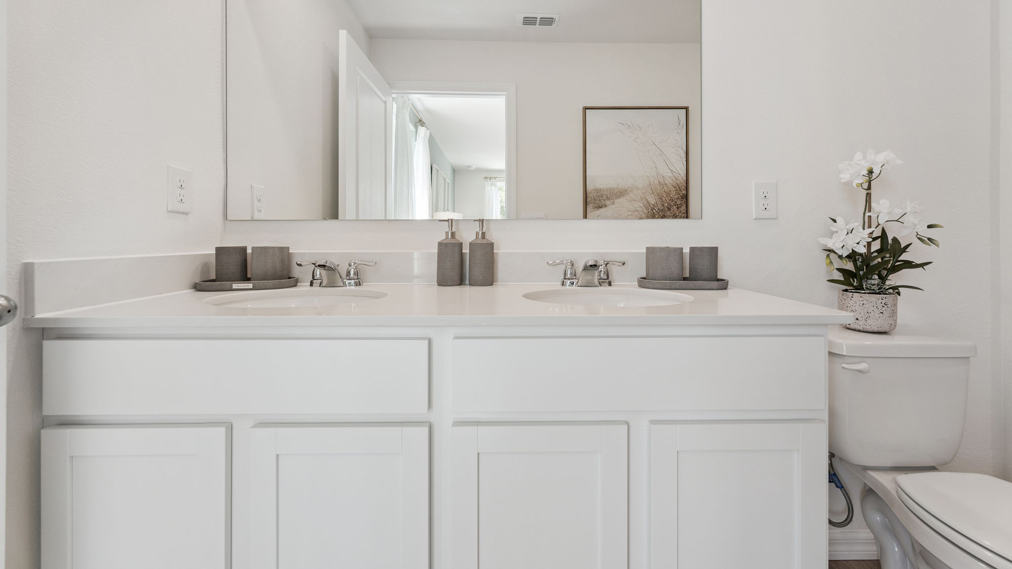 Modern bathroom with double vanity, large wall mirror, cabinets and quartz countertops