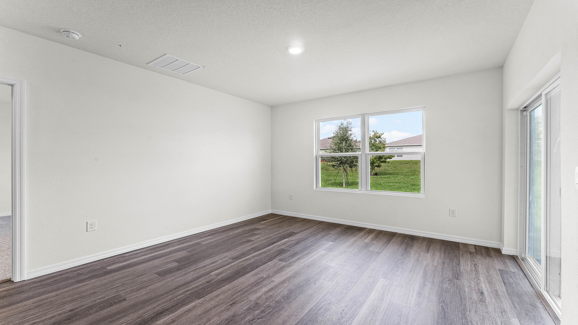 Open concept living area with couch seating and access to the backyard thru slider door.