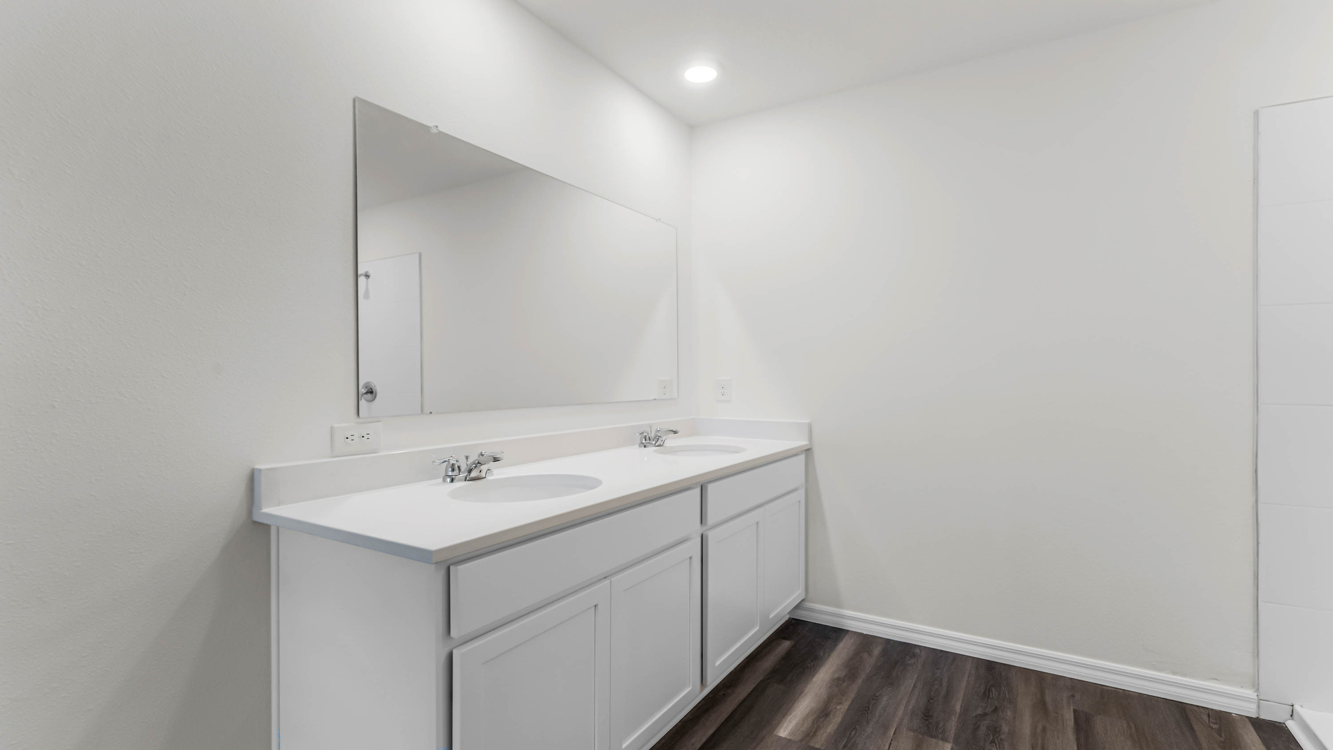 Modern bathroom with double vanity sinks, large wall mirror, cabinets and granite countertops.