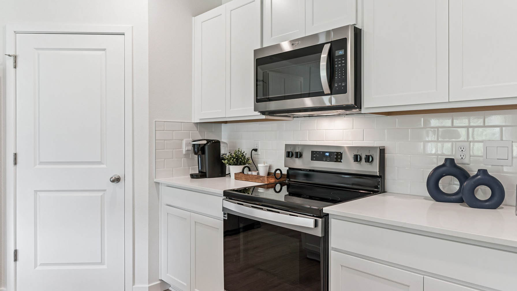 Kitchen with island seating, quartz counters, spacious pantry and stainless steel appliances.