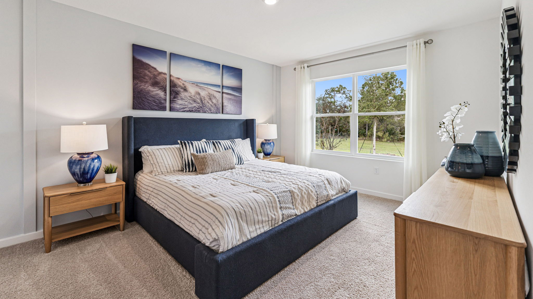 Guest bedroom with bed, nighstands and natural lighting.