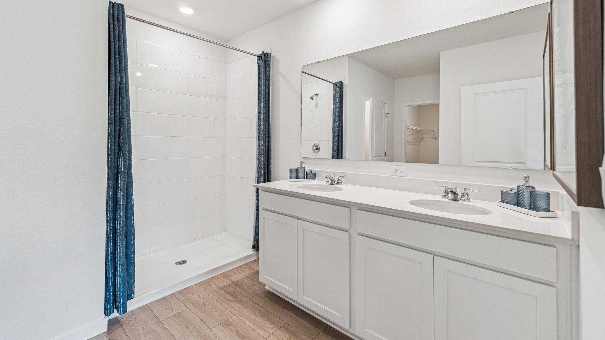 Modern bathroom with double vanity, large wall mirror, cabinets and quartz countertops