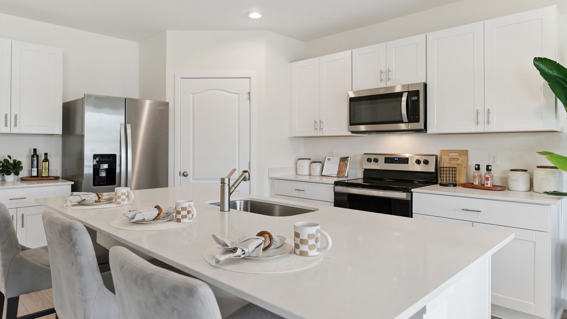 Kitchen with island seating, quartz counters, spacious pantry and stainless-steel appliances.
