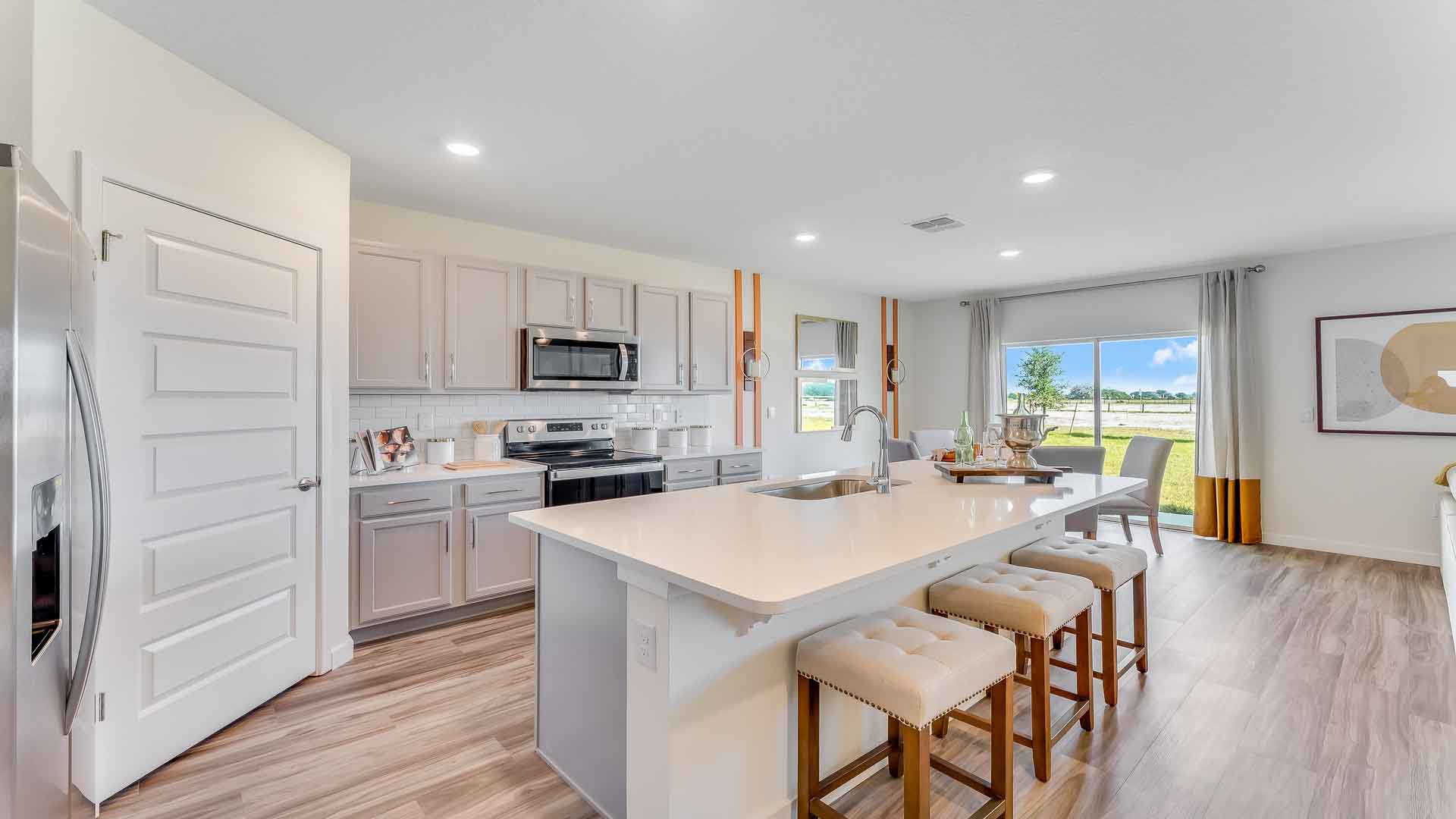 Kitchen with island seating, granite counters, spacious pantry and stainless-steel appliances.