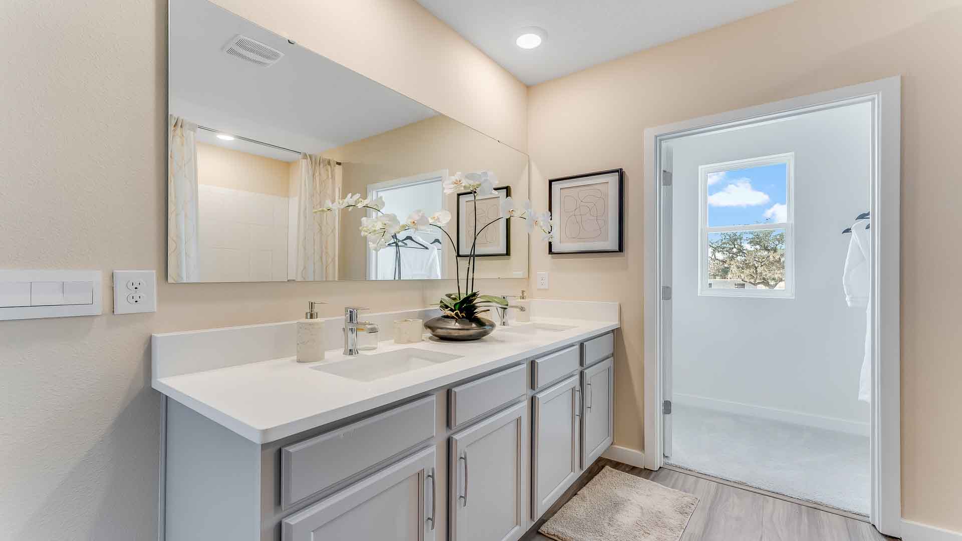 Modern bathroom with double vanity sinks, large wall mirror, cabinets and granite countertops.