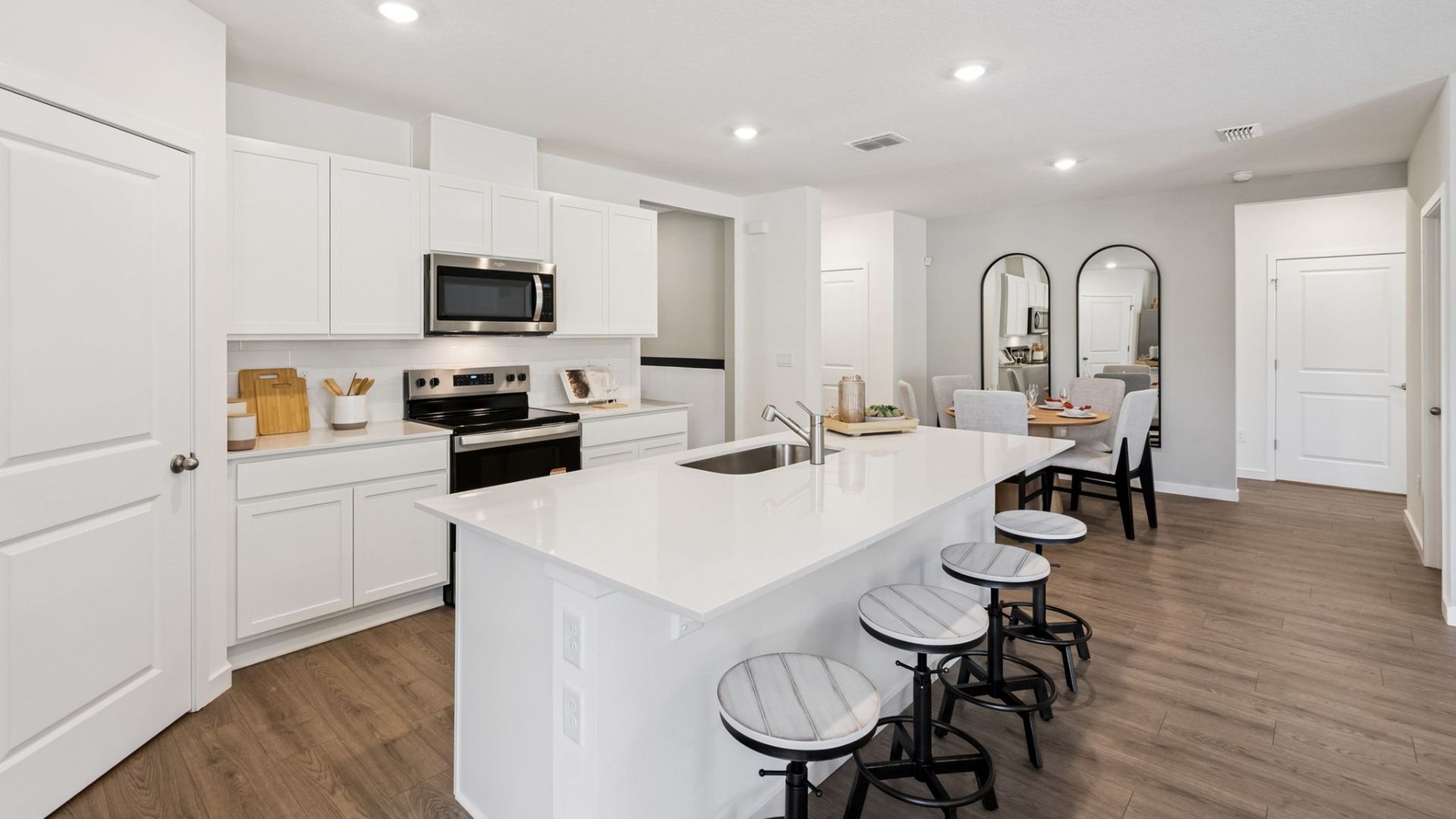 Kitchen with island seating, quartz counters, spacious pantry and stainless steel appliances.