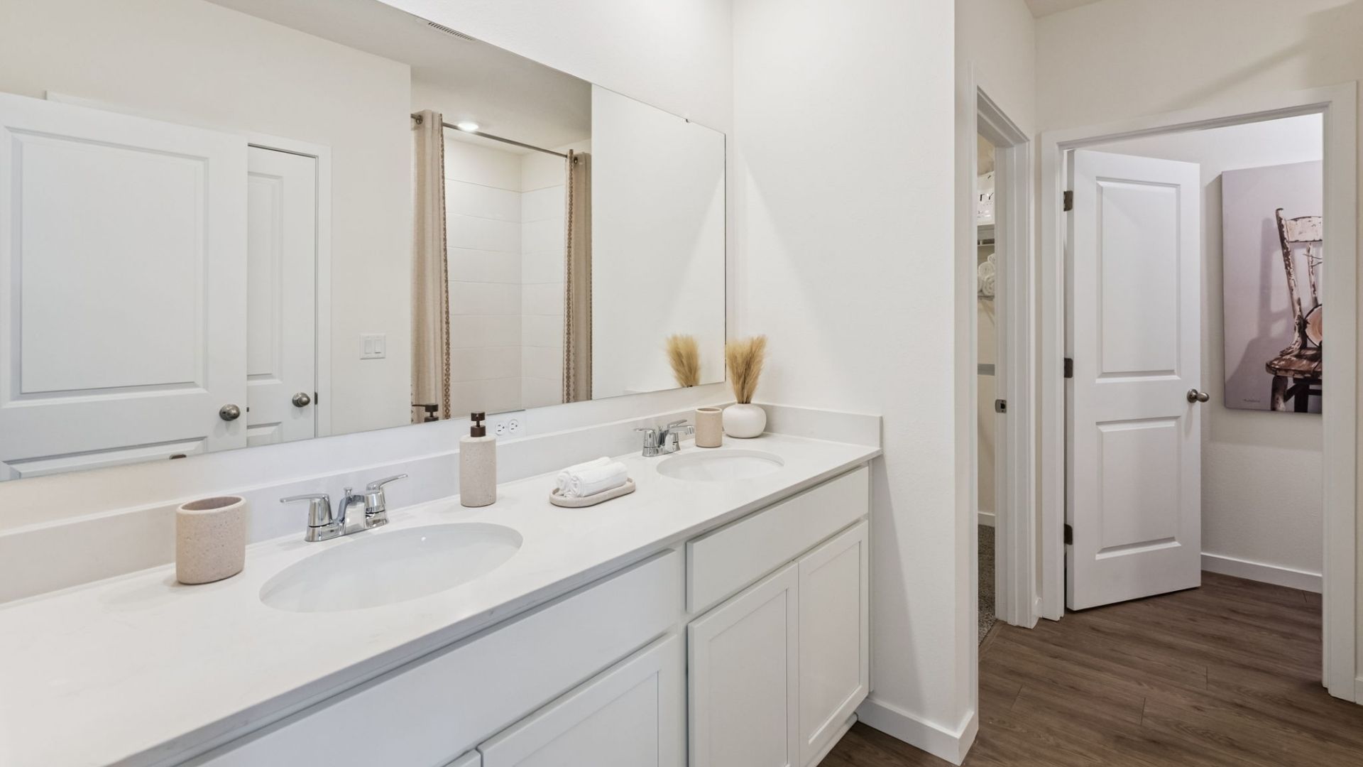 Modern bathroom with single vanity, large wall mirror, cabinets and quartz countertops and laminate flooring