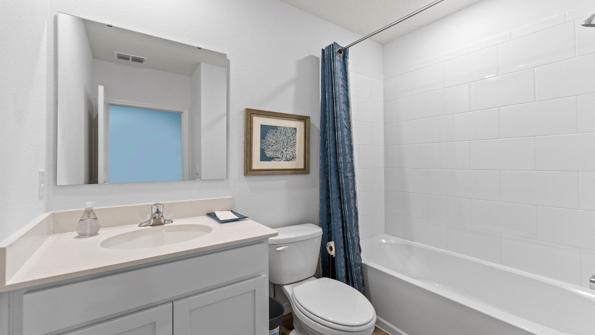 Modern bathroom with double vanity, large wall mirror, cabinets and quartz countertops along with toilet and walk-in shower