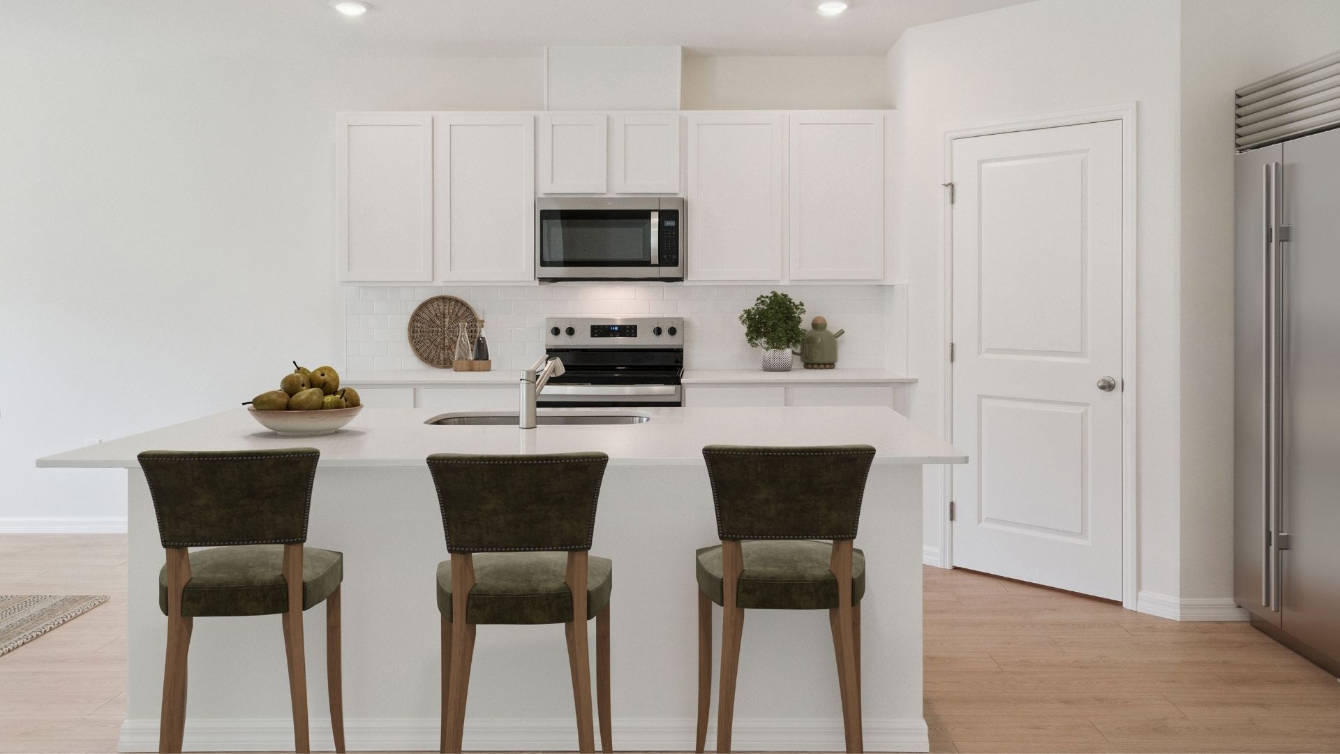 Kitchen with island seating, quartz counters, spacious pantry and stainless steel appliances.