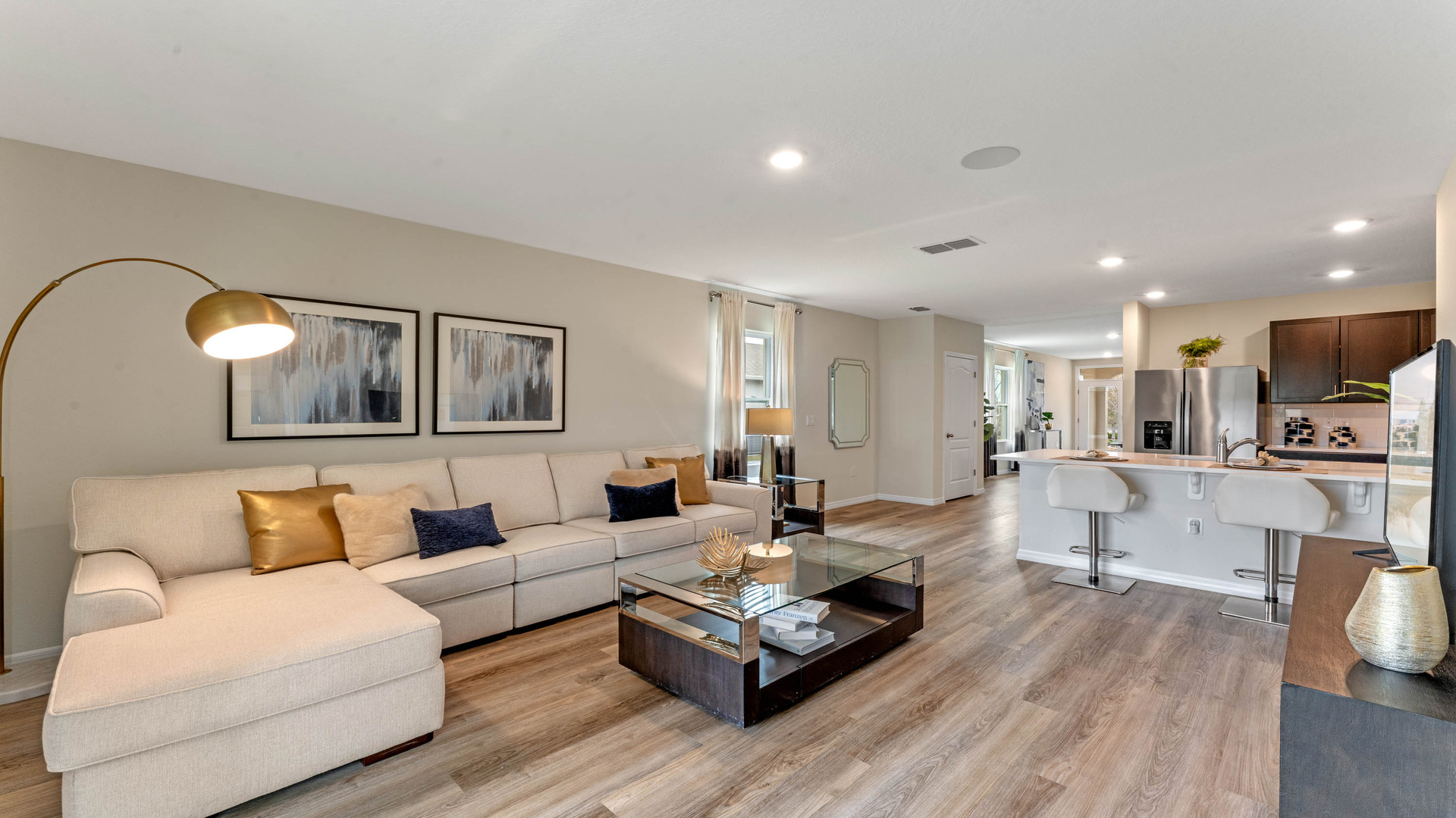 Living area with couch seating, entertainment system and natural lighting overseeing kitchen and dining room