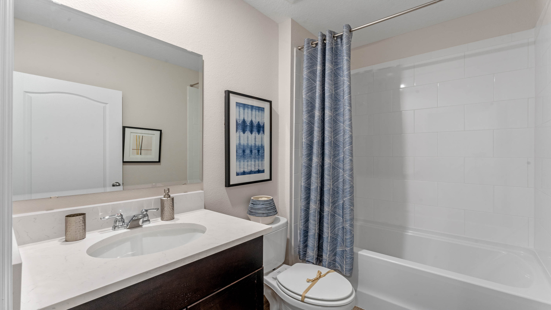 Modern bathroom with single vanity, large wall mirror, cabinets and quartz countertops
