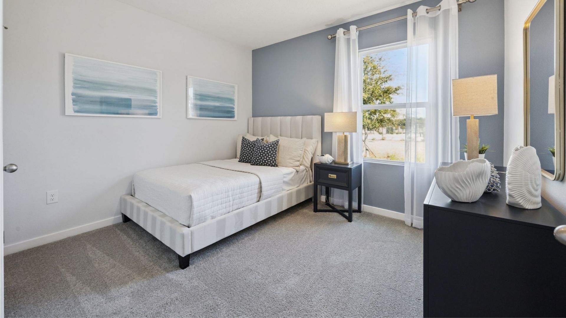 Spacious primary bedroom with king size bed, carpet flooring, natural lighting.