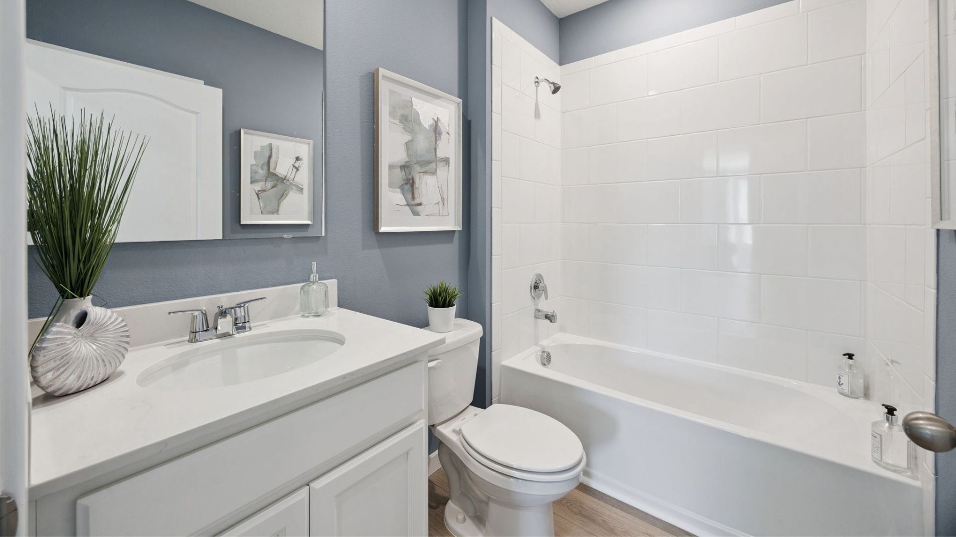 Modern bathroom with single vanity, large wall mirror, cabinets and quartz countertops
