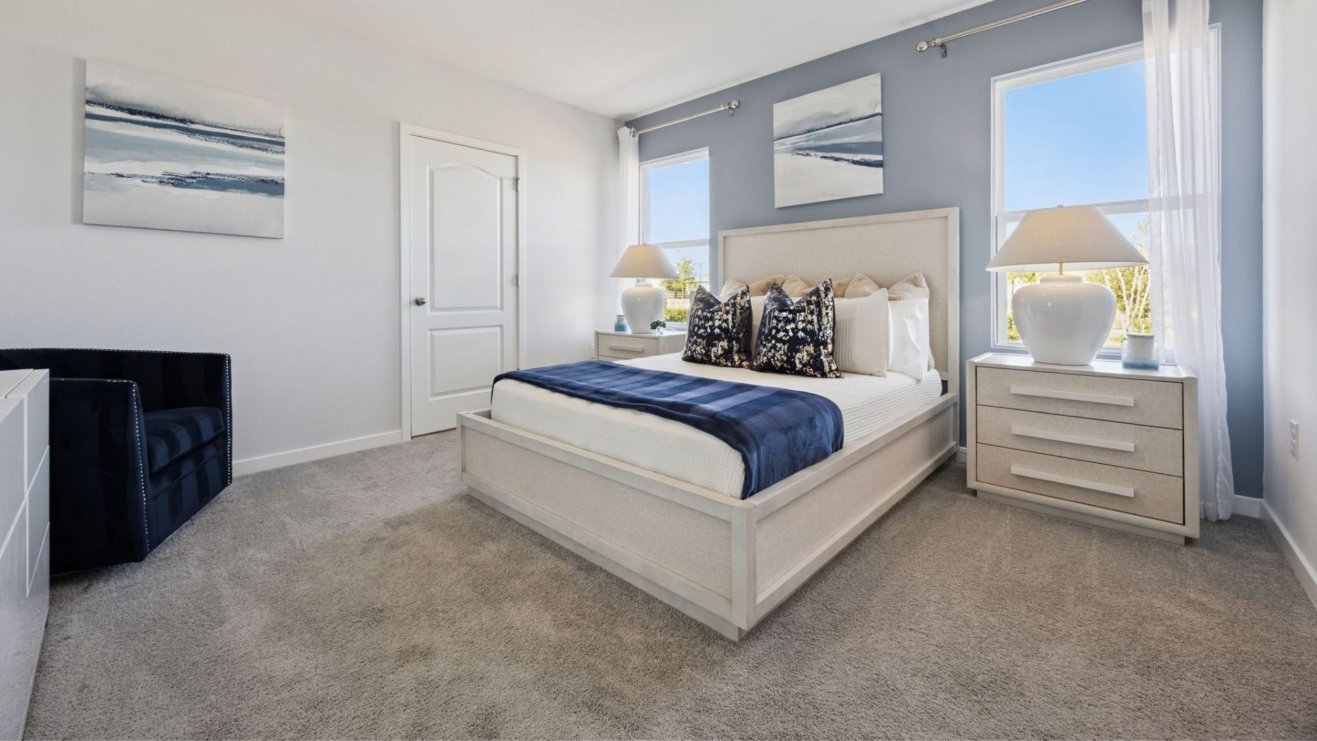 Spacious primary bedroom with king size bed, carpet flooring, natural lighting.