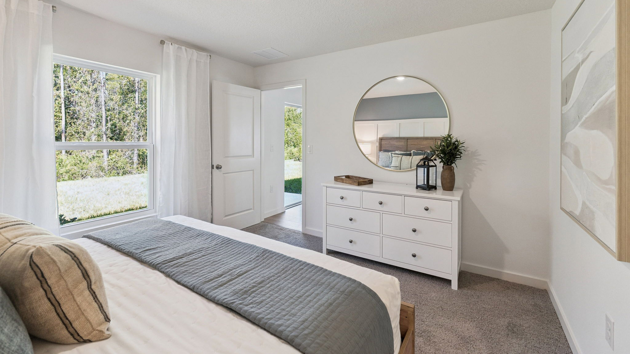 Spacious primary bedroom with king size bed, carpet flooring, natural lighting.