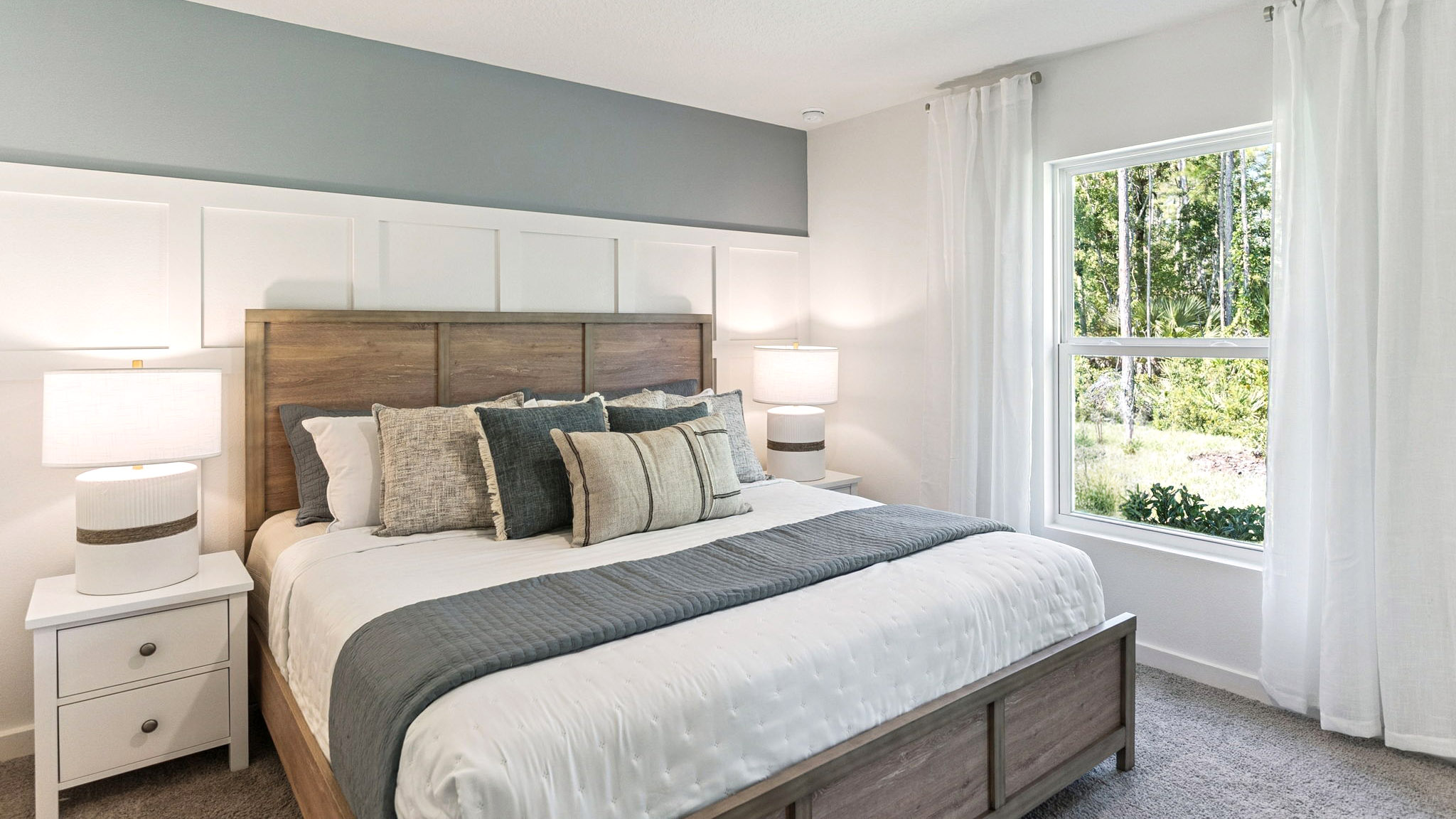 Spacious primary bedroom with king size bed, carpet flooring, natural lighting.