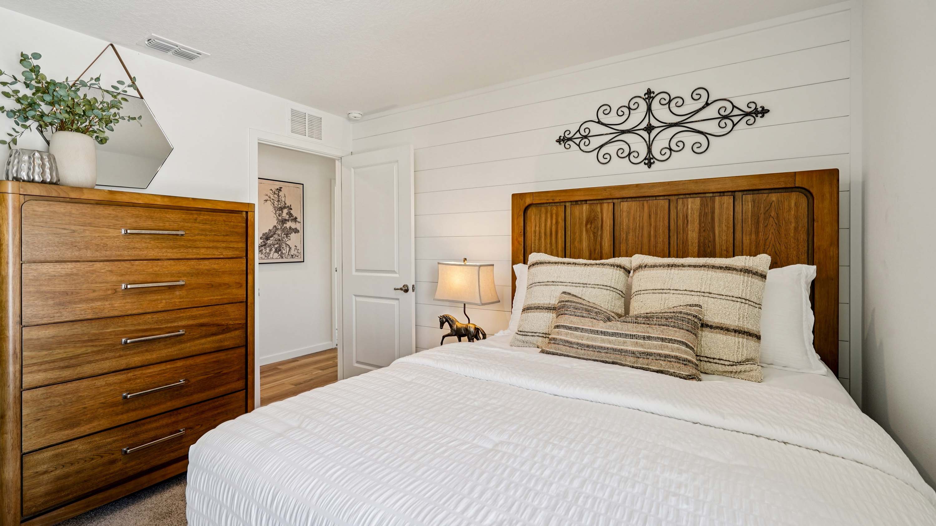 Spacious primary bedroom with bed, carpet flooring, natural lighting showing access to primary bathroom.