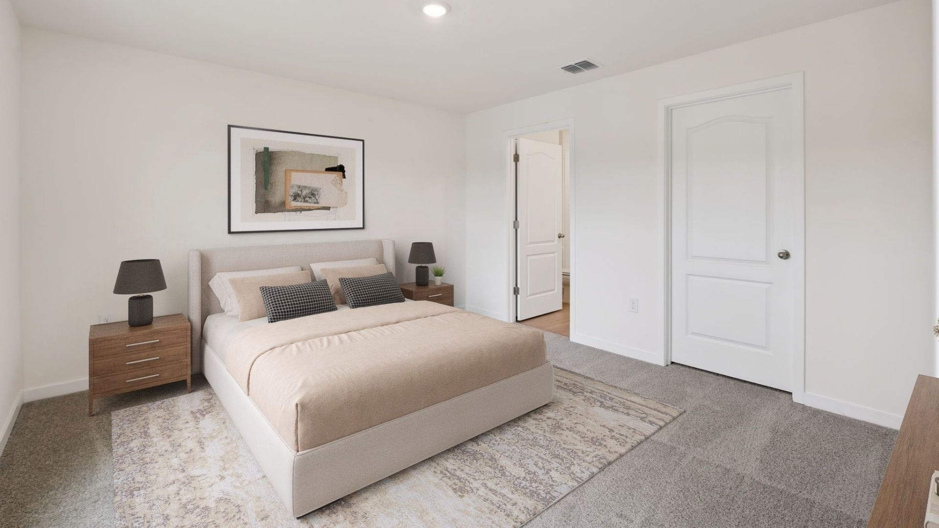 Spacious primary bedroom with king size bed, carpet flooring, natural lighting.