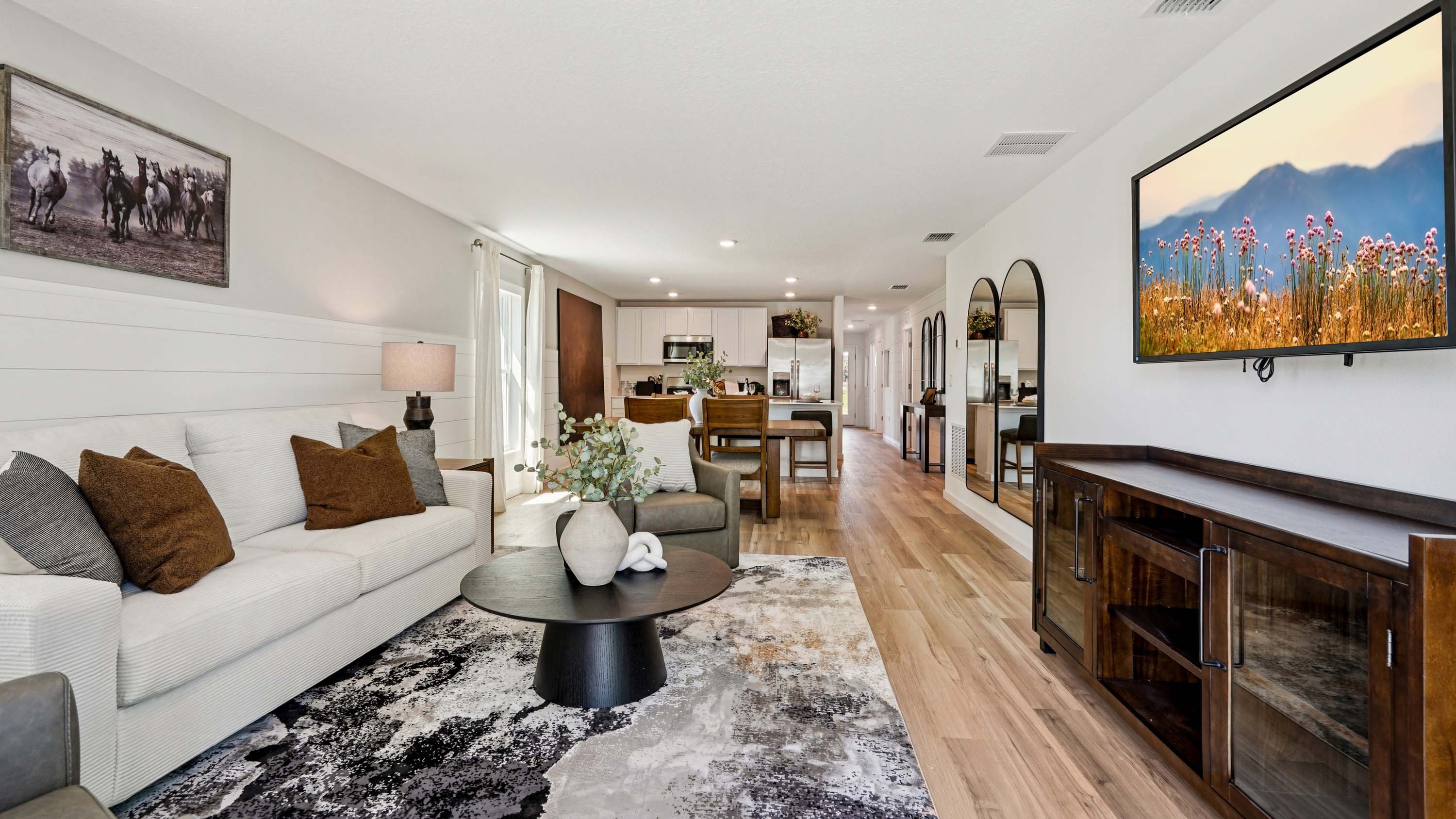 Living area with seating, entertainment system and natural lighting overseeing dining room table and kitchen
