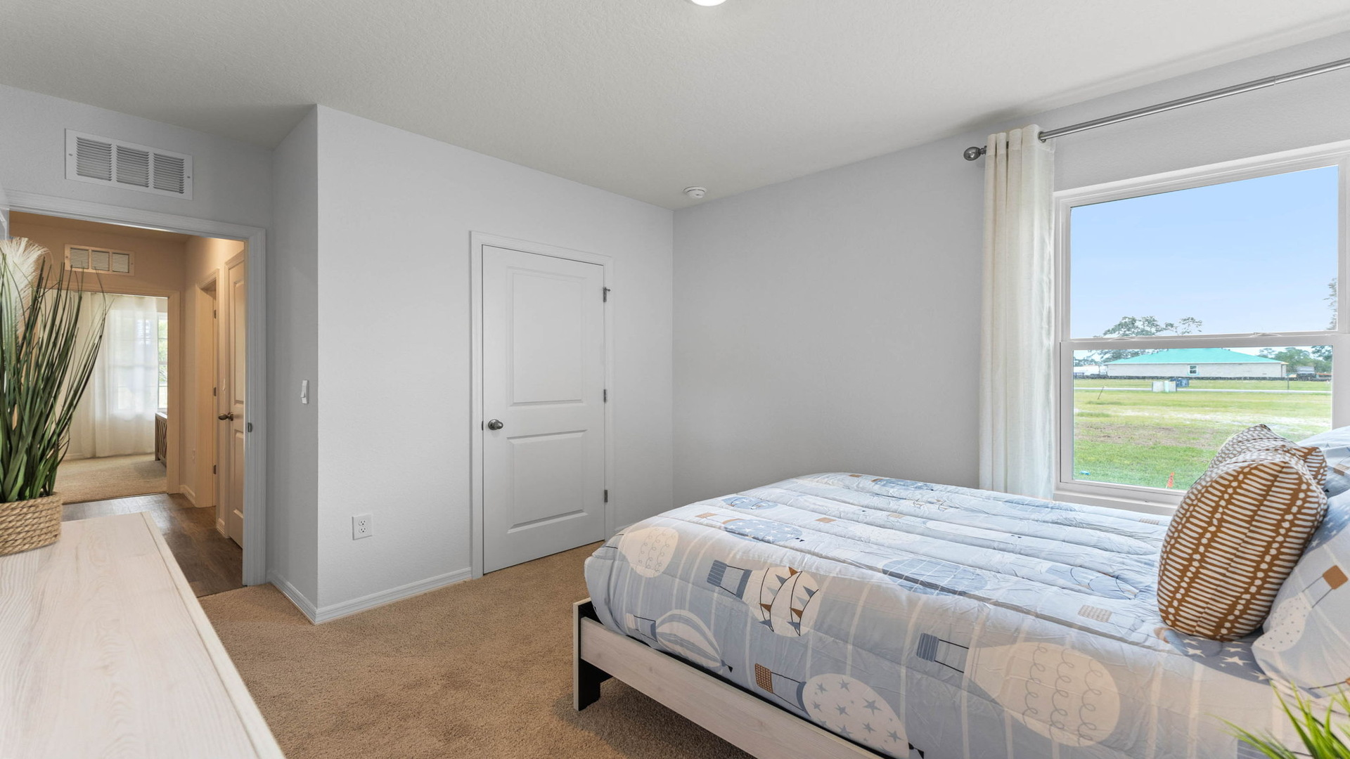 Guest bedroom with bed, nighstand, desk, and natural lighting with spacious closet.