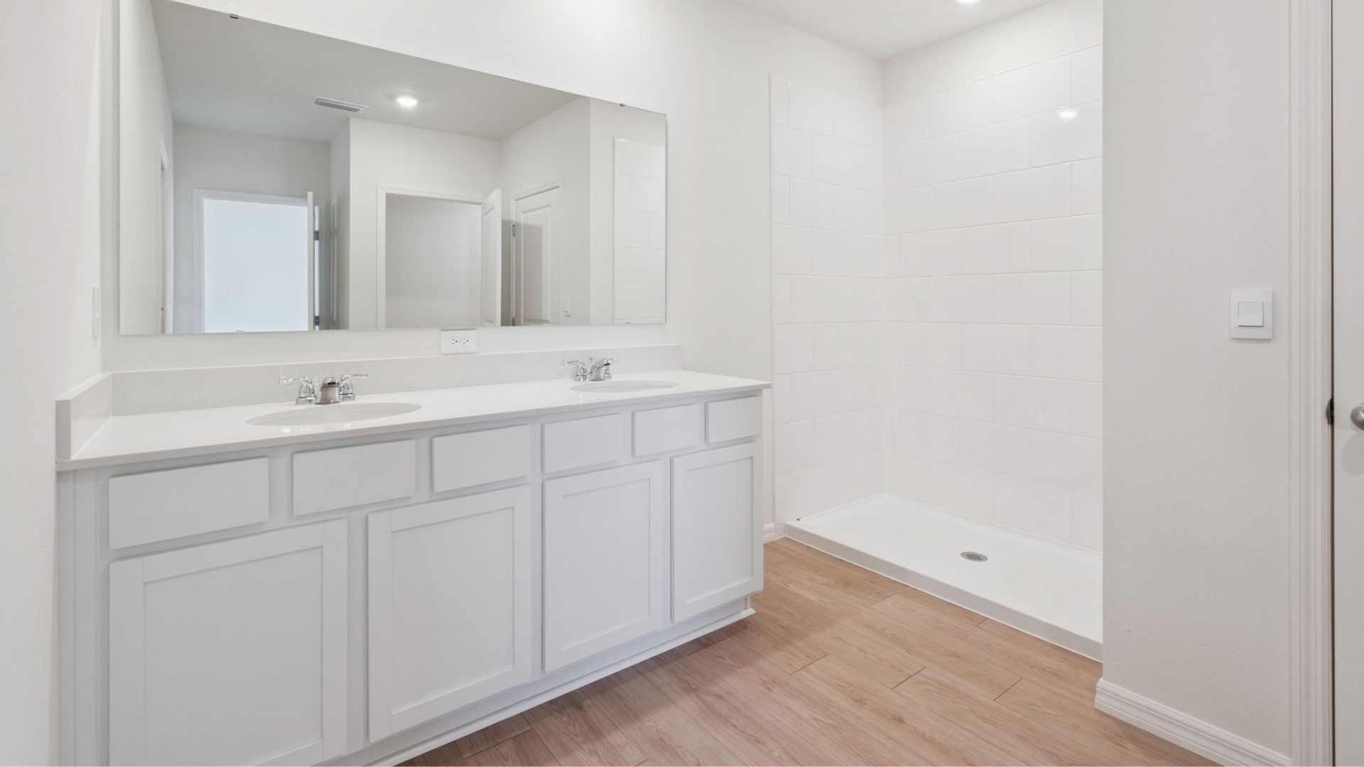 Modern bathroom with double vanity, large wall mirror, cabinets and quartz countertops