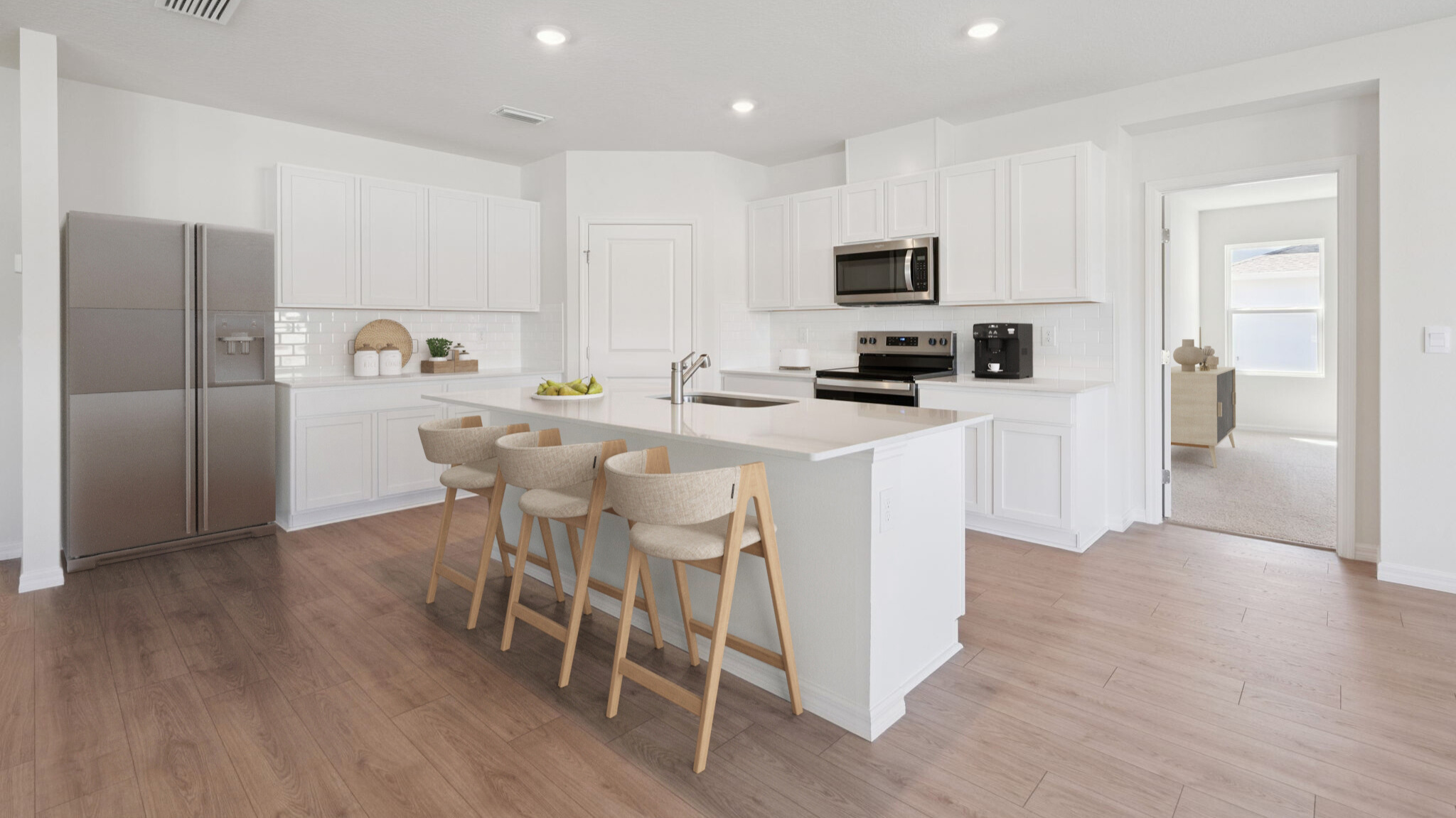 Kitchen with island seating, quartz counters, spacious pantry and stainless steel appliances.