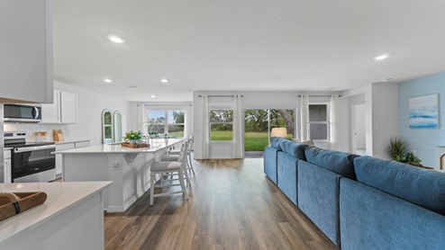 Kitchen with island seating, quartz counters, spacious pantry and stainless steel appliances showing entry way to home overseeing dining room
