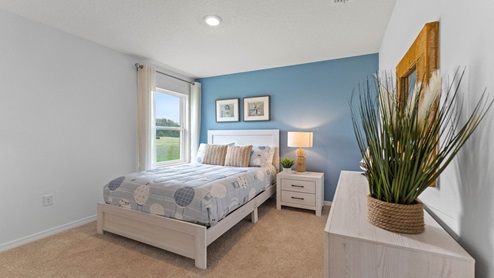 Guest bedroom with bed, nighstand, desk, and natural lighting with spacious closet.