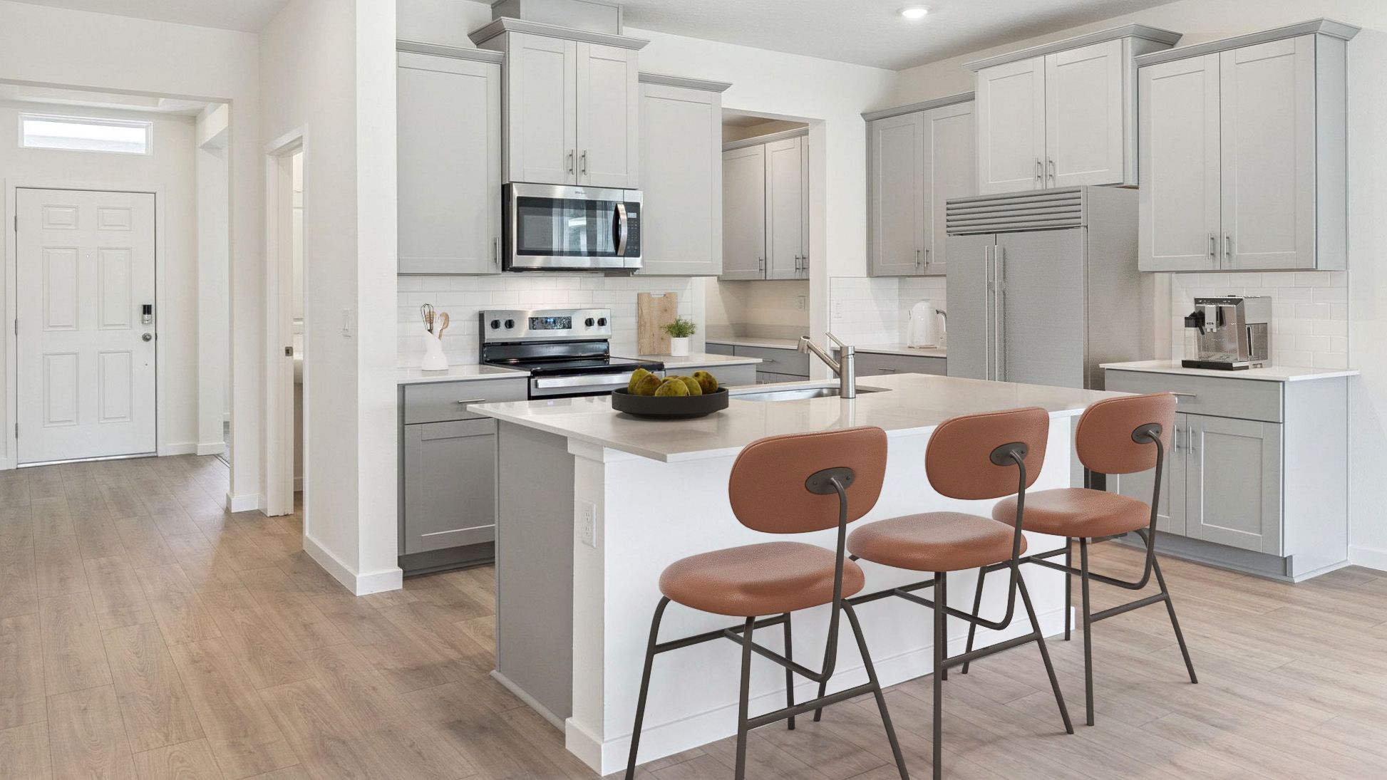 Kitchen with island seating, quartz counters, spacious pantry and stainless steel appliances.