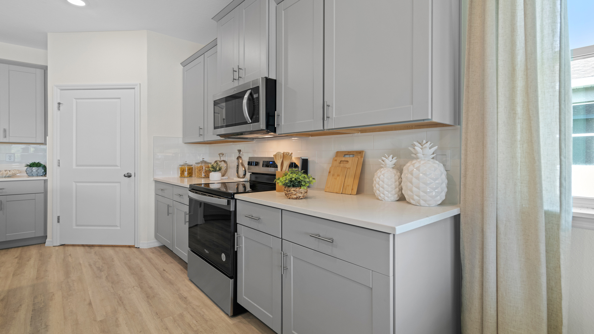 Kitchen with tall cabinetry, appliances, walk in pantry and Luxury vinyl plank flooring.