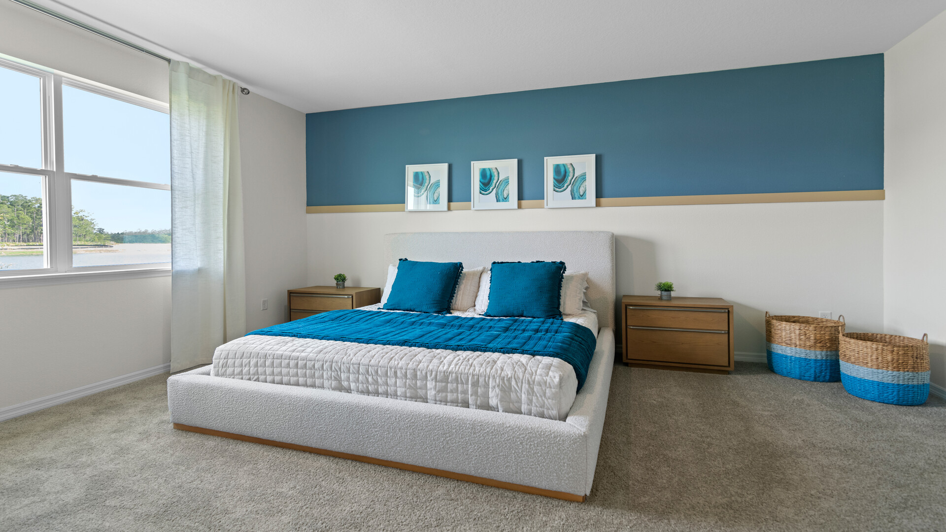 Spacious primary bedroom with king size bed, carpet flooring, natural lighting.