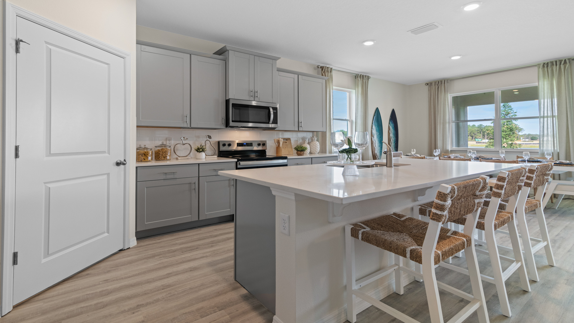 Kitchen with island seating, quartz counters, spacious pantry and stainless steel appliances.