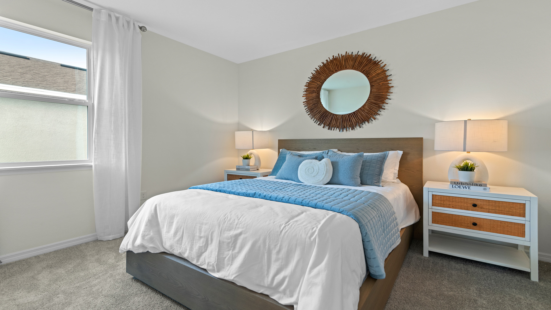 Spacious primary bedroom with king size bed, carpet flooring, natural lighting.