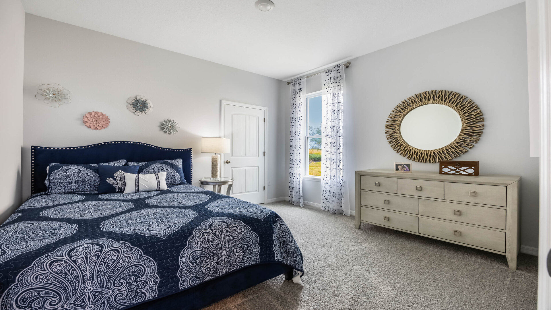 Guest bedroom with bed, nighstand, desk, and natural lighting with spacious closet.