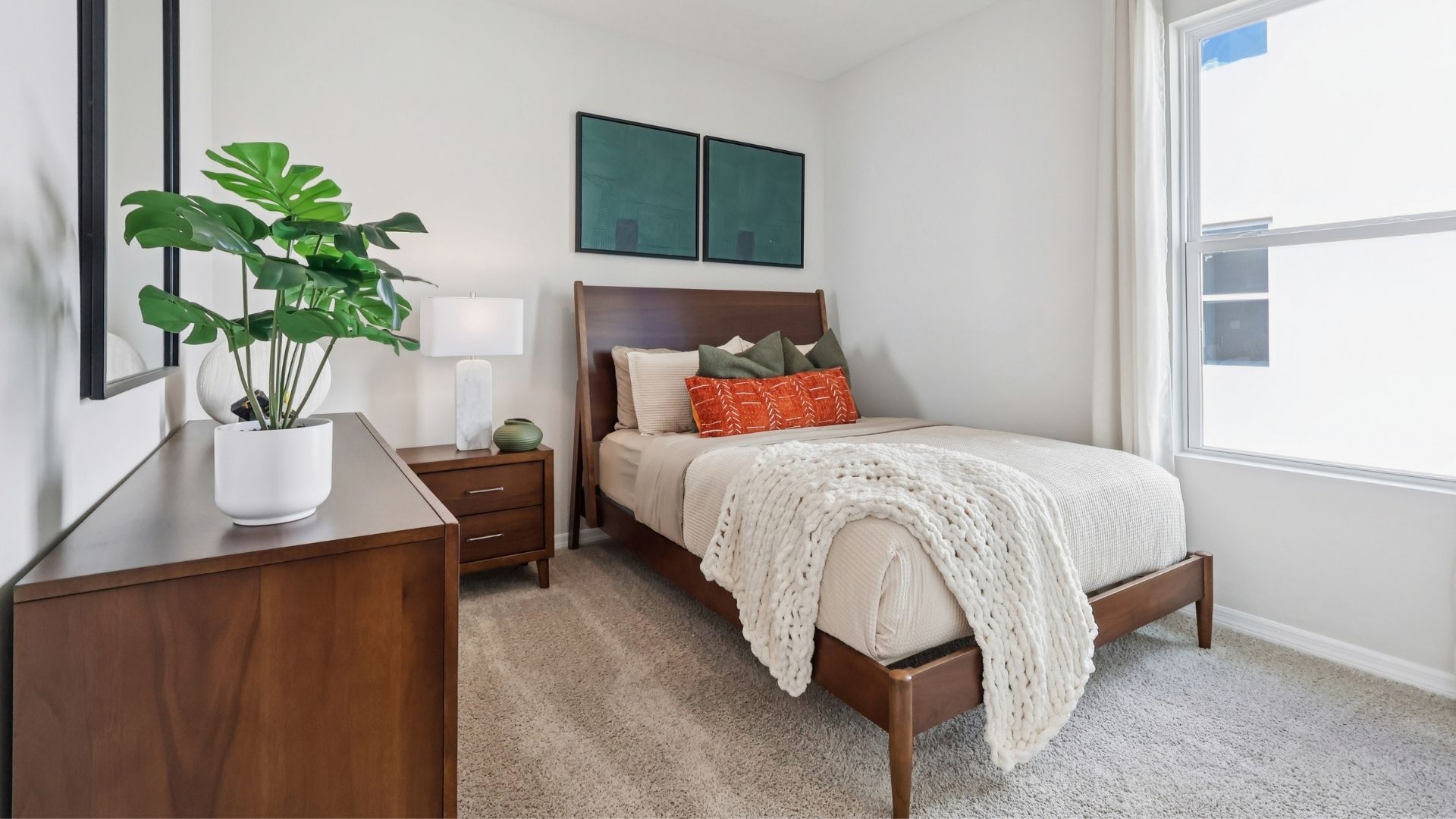 Spacious primary bedroom with king size bed, carpet flooring, natural lighting.