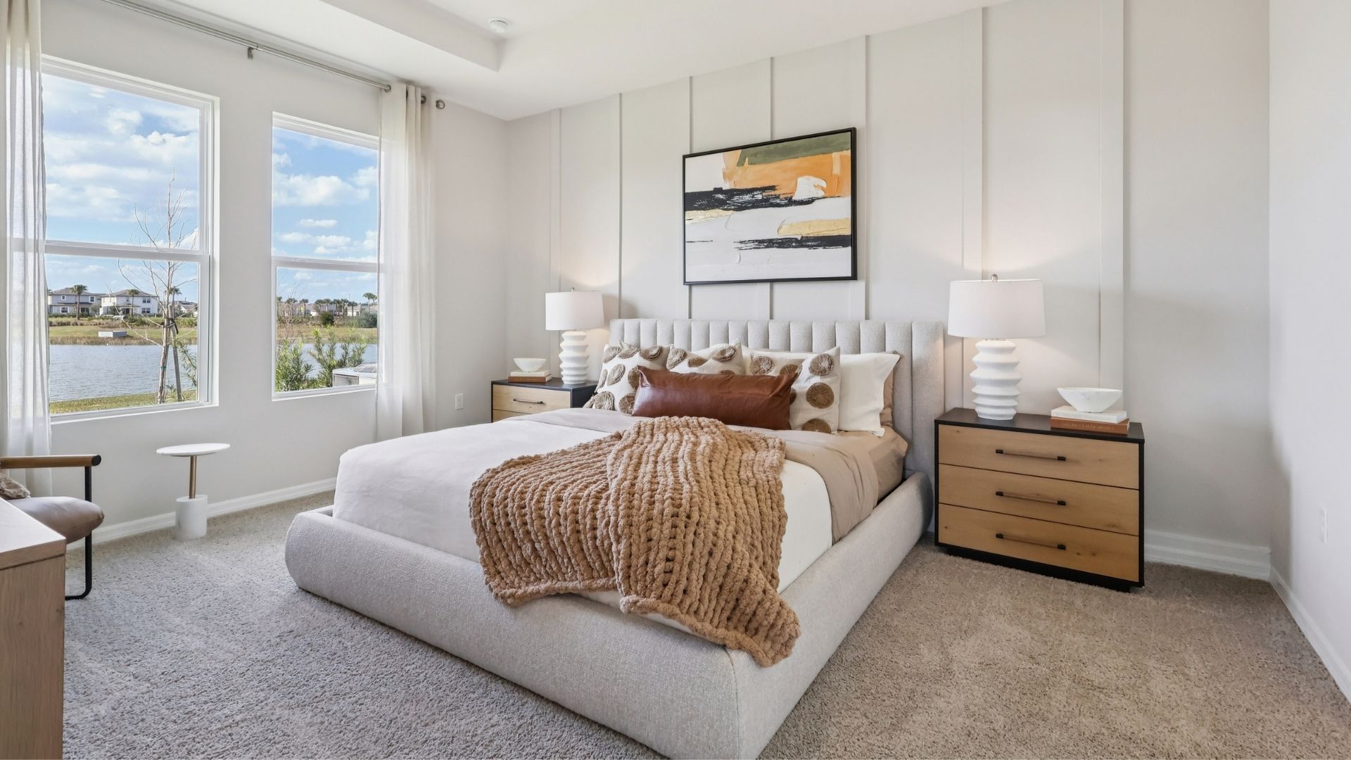 Spacious primary bedroom with king size bed, carpet flooring, natural lighting.