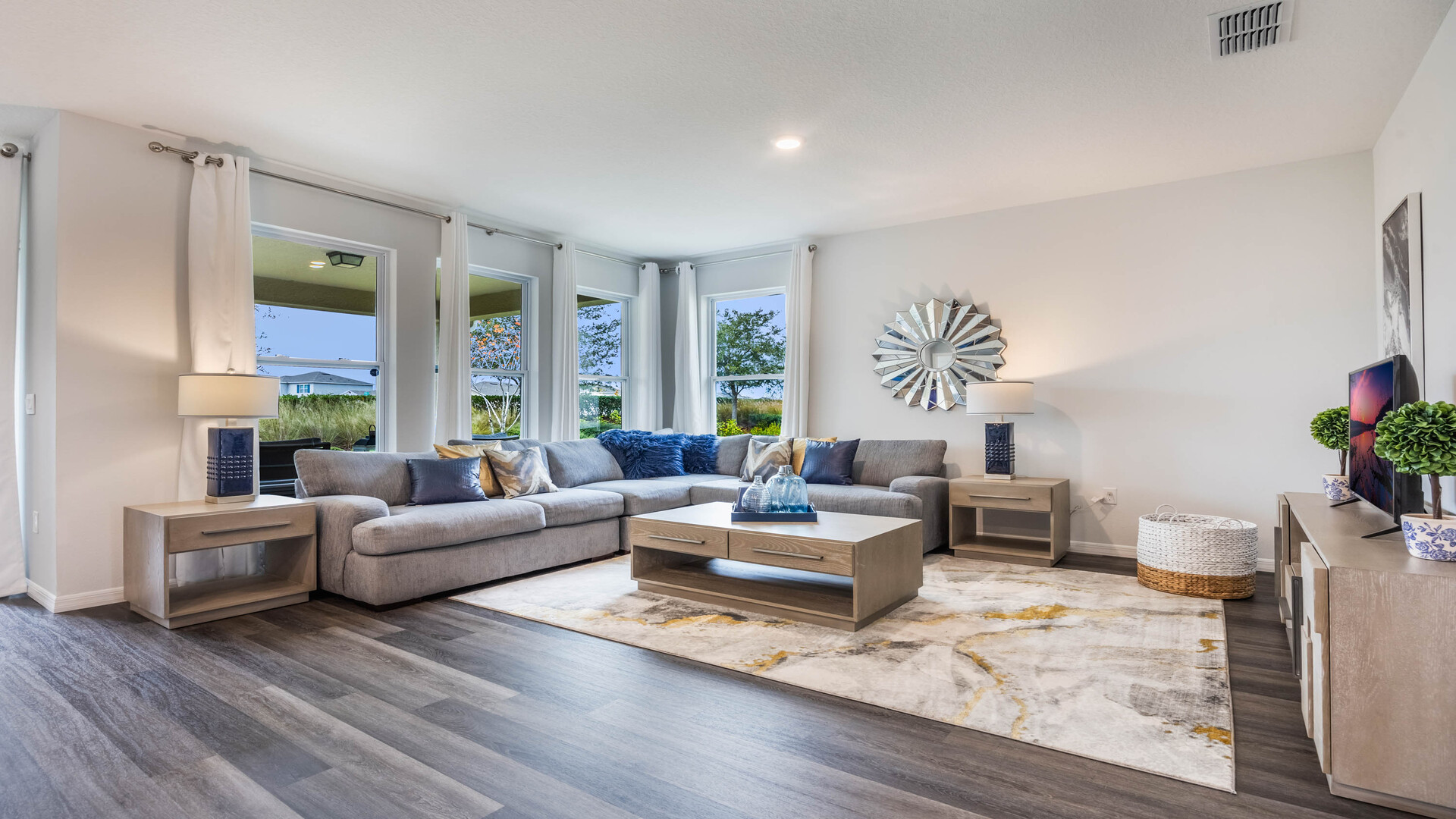 Kitchen with island seating, quartz counters, spacious pantry and stainless steel appliances showing entry way to home overseeing living area.