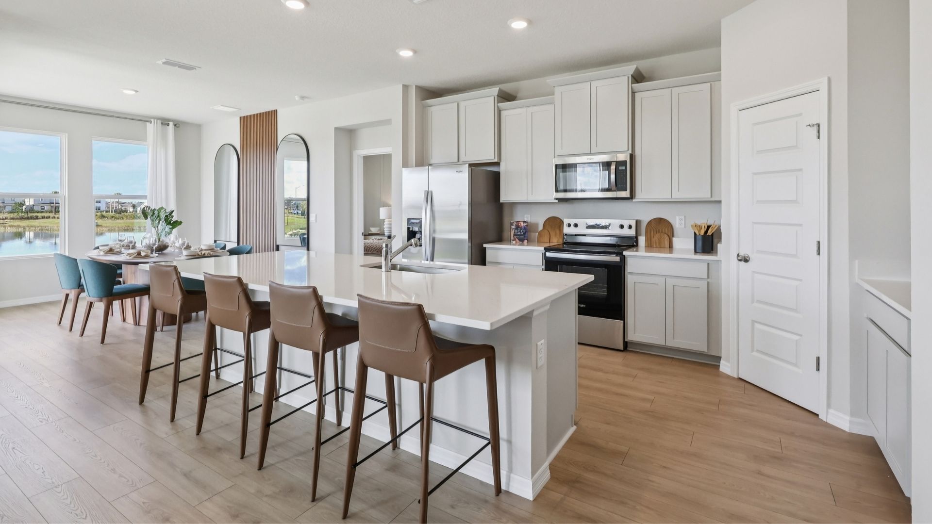 Kitchen with island seating, quartz counters, spacious pantry and stainless steel appliances.