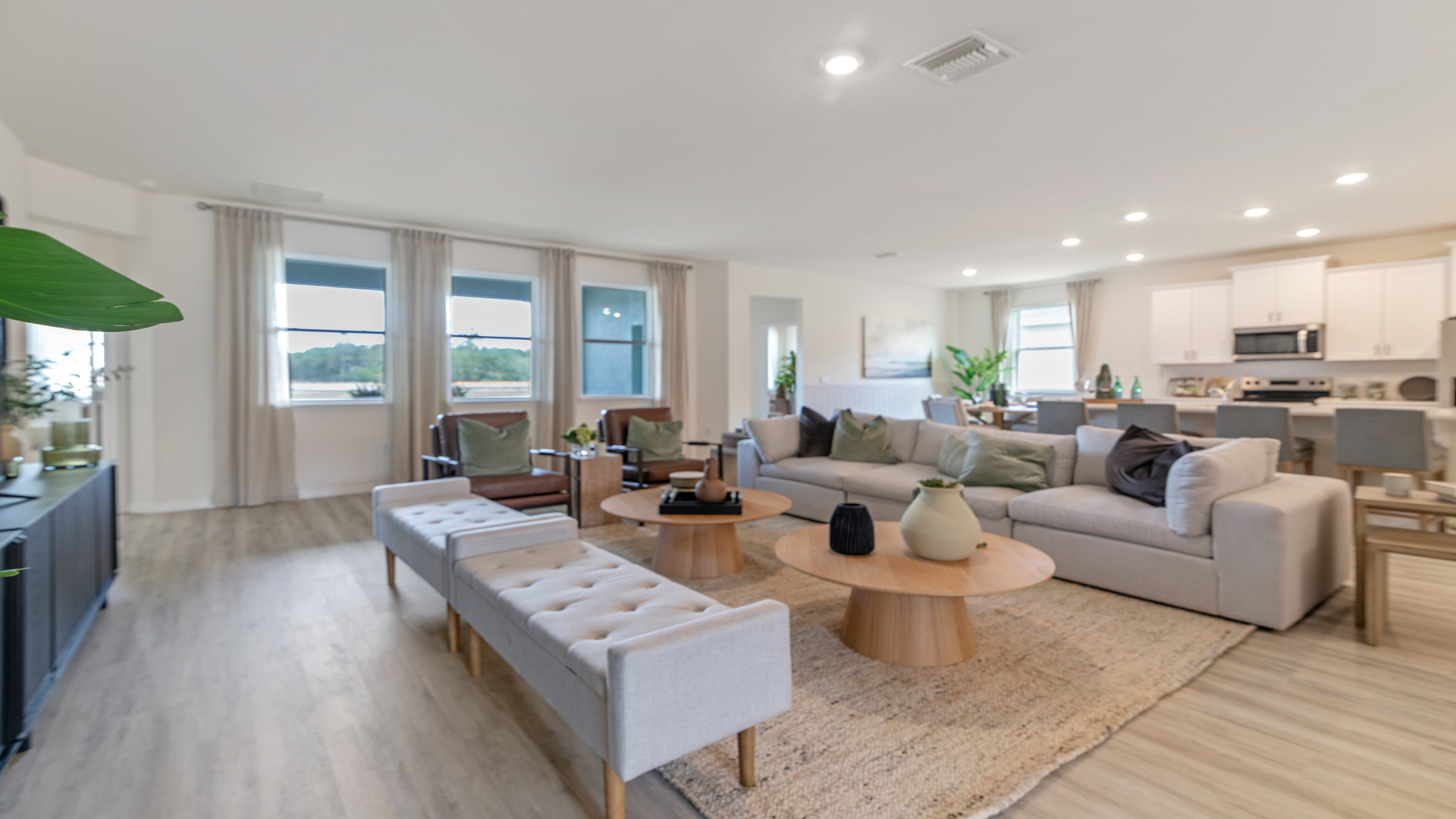 Living area with couch seating, entertainment system overseeing kitchen and dining room table.